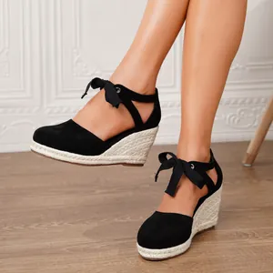 Elegantes sandalias de cuña tipo esparteña en lona negra con un bonito lazo al tobillo.