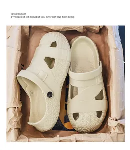 Nahaufnahme von beigen Designer-Clogs in einer rustikalen, mit Papier ausgelegten Box.