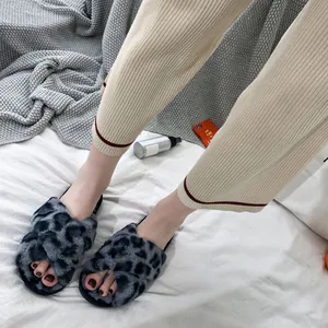 Detail view showing leopard print faux fur cross-strap slippers in a cozy home setting