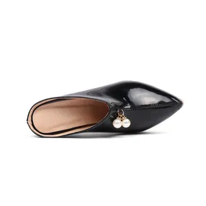 Detailed view of black patent leather pointed-toe mules with elegant pearl bead charms.
