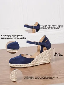 Dettaglio di sandali con zeppa blu navy con tacchi in paglia e cinturini con fibbia regolabile.