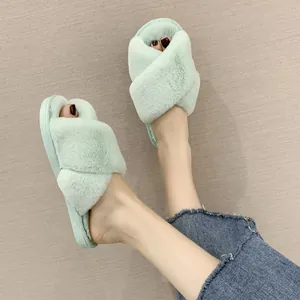On-foot view of mint green fuzzy cross-strap slippers with soft faux fur texture detail
