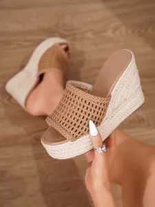 Detalle de cerca de la tira tejida marrón para mujer y suela de cuña envuelta en yute