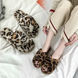 Detail shot of leopard print plush cross-strap house slippers on white fabric background