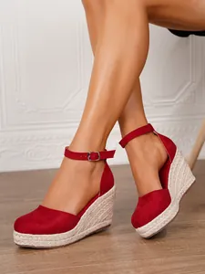 Primer plano de sandalias de cuña rojas de gamuza con suela de cuerda de yute trenzada