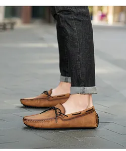Vue latérale de mocassins en cuir marron portés sur un fond de rue pavée extérieure