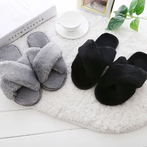 Cozy fuzzy cross-strap slippers in grey and black on a white shaggy rug.