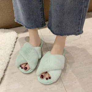 Detailed view of mint green faux fur cross-strap slippers worn indoors with jeans