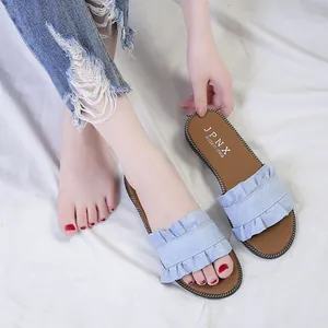 Close-up of light blue ruffled flat slides for women in a summer setting