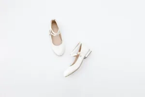 Elegant white Mary Jane flat shoes featuring cross straps and pearl buckle accents