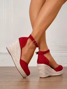 Sandalias de cuña rojas de ante con punta cerrada y correas en el tobillo, detalle.