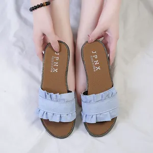 Detailed close-up of light blue ruffled flat slippers with stylish wood ear trim