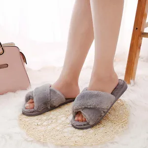 Detail view of grey plush cross-strap slippers being worn indoors on a soft rug