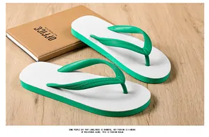 Close-up of stylish green and white rubber flip-flops placed on a wooden surface with a notebook