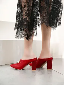 Detail view of red pointed-toe mules with chunky heels and pearl embellishment.