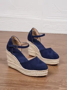 Detailaufnahme blauer Keilsandaletten aus Wildleder mit geflochtener Jute-Plattform und Riemen.