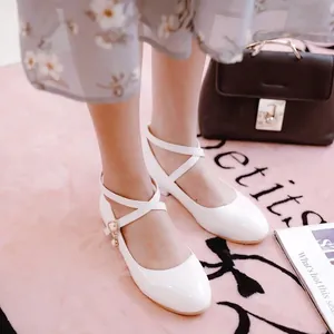 Detail view of white patent leather Mary Jane shoes with elegant cross strap design