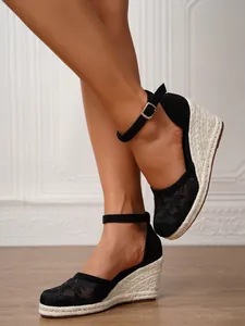 Detalle de sandalias de cuña de encaje negro con correa al tobillo para las vacaciones