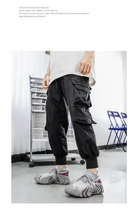 Detail view of grey fly-knit sneakers paired with black cargo pants in studio