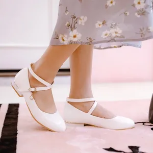 Close-up of white girls' Mary Jane flats with cross straps and pearl charm detail