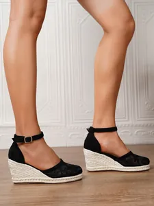 Detalle de sandalias de cuña con encaje negro, suela de yute y correa de tobillo