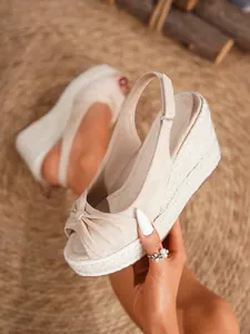 Detalle de sandalias con cuña tipo alpargata en ante beige con nudo y punta abierta
