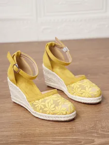 Vista detallada de las sandalias de cuña amarillas con bordado floral para mujer