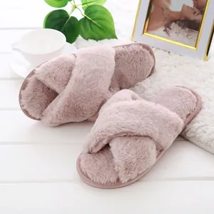 Close-up of pink fuzzy cross-strap slippers on a cozy white home setup.