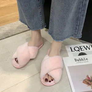 Close-up of stylish pink fuzzy cross-strap slippers on feet for indoor home comfort