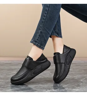 Side view close-up of black slip-resistant work shoes with velcro straps on model's feet