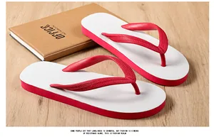 Top view of red and white rubber flip-flops placed on a wooden desk with a brown notebook