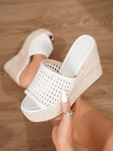 Detalle de sandalias de cuña tejidas blancas con suela de plataforma de paja tejida