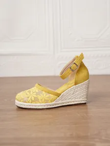 Alpargatas de cuña amarillas con bordado floral y correa al tobillo, vista lateral.
