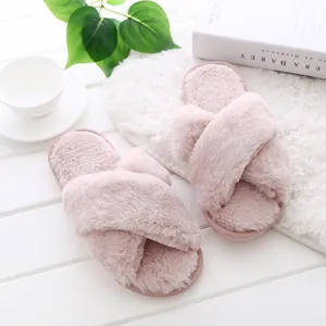 Detailed macro view of pink fuzzy cross-strap home slippers with soft plush texture.