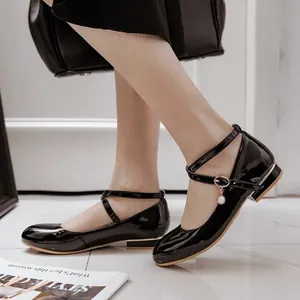 Elegant black patent leather Mary Jane flats with pearl charm on cross ankle straps.