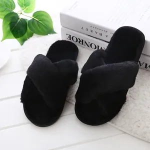 Close-up of black fuzzy cross-strap slippers showing soft faux fur texture for home