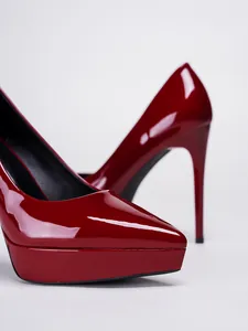 Detailed macro shot of elegant red patent leather platform pumps with sexy stiletto heels.