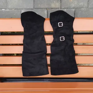 Detailed view of black suede over-the-knee boots with stylish metal buckle accents