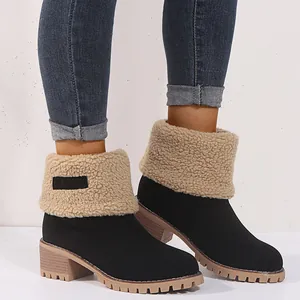 Detail view of black snow boots with warm beige sherpa fold-over cuffs and lug soles.