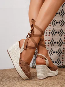 Primer plano de sandalias de cuña de ganchillo marrón con lazos estilo boho.