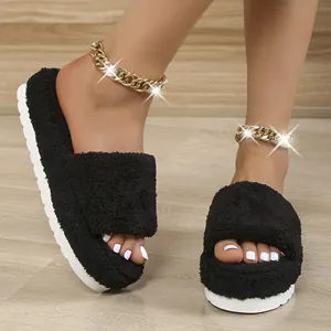 Close-up of black fuzzy platform slides with plush faux fur on a wooden floor.