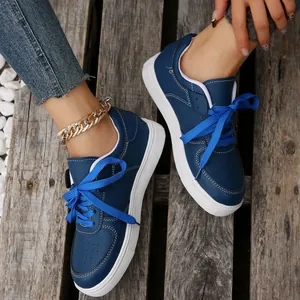Nahaufnahme blauer Damen-Freizeitschuhe mit blauen Schnürsenkeln auf Holzboden