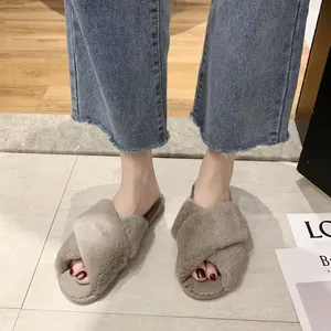 Close-up detail of women's taupe furry crossover slippers worn on a tiled floor