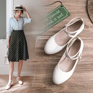 Detailed view of white Mary Jane shoes with cross straps on a model and wooden floor