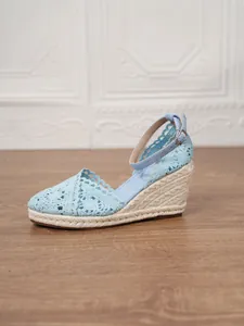 Detalle de sandalias de cuña con encaje de ganchillo azul y tacón de esparto