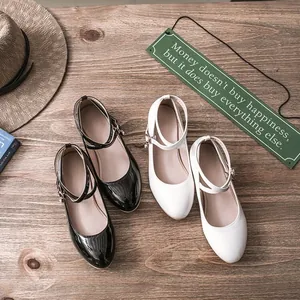 Detail view of black patent and white matte Mary Jane shoes with elegant cross ankle straps