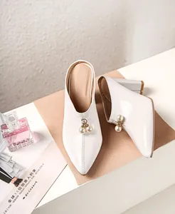 Detailed view of white pointed-toe block heel mules with elegant pearl charms