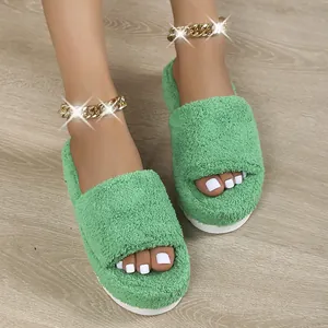 Detailed view of green fuzzy platform slippers worn on feet featuring gold chain anklets