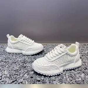 Close-up of white breathable men's outdoor sneakers with woven texture on gravel