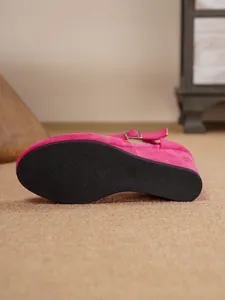Detailansicht der schwarzen profilierten Laufsohle einer pinkfarbenen Keilsandalette